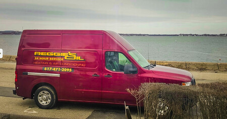 Reggie's Oil Service Van parked by the waterfront, offering 24-hour heating and air conditioning service.